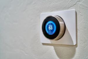 Smart thermostat on wall with temperature display and mobile app for energy saving and heating comfort
